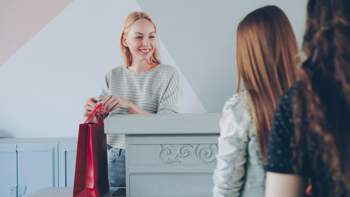 Shop assistant handing shopping bag to customers